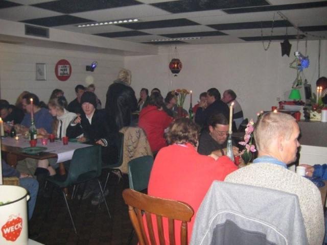 De bezoekers en vrijwilligers eten en kletsen aan de gezellig gedekte tafels.