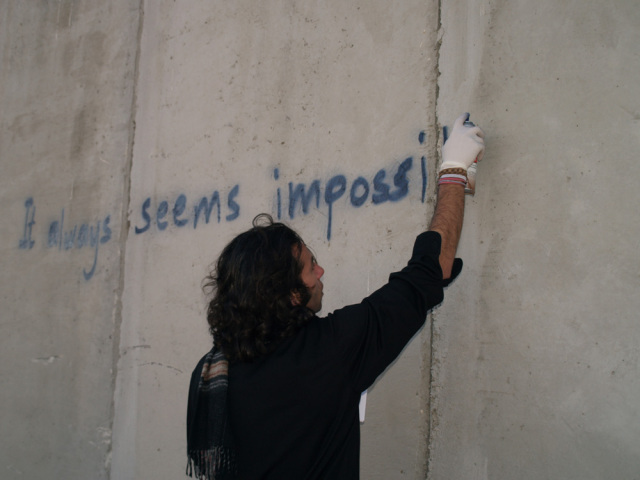 Palestijn spuit een leus op de muur