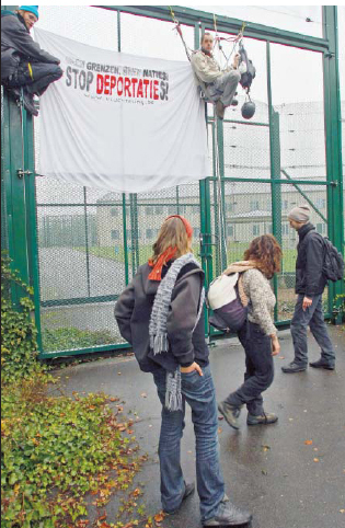 twee activisten blijven letterlijk hangen aan het hekken van het centrum.