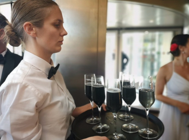 Waitress serving black bhampagne at the Cultural Opening