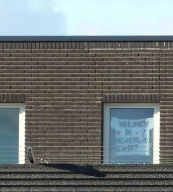 DC Rotterdam during demo: prisoner holds a sign saying: Freedom? Not in NL